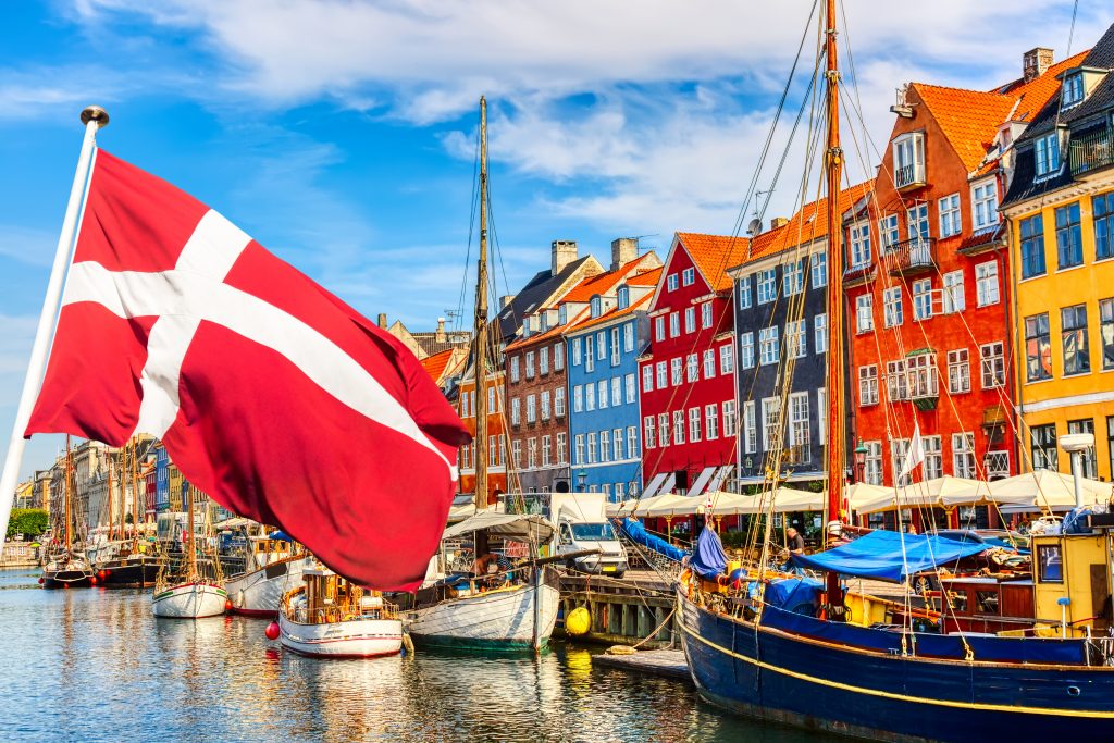Színes házsor a folyómentén és a dán zászló