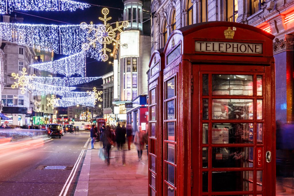 Piros telefonfülkék egy karácsonyi égősorral feldíszített utcán